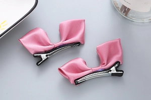 Vue détaillée des barrettes à nœuds en satin rose avec pinces crocodiles robustes