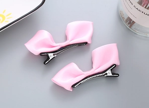 Détail des barrettes nœuds en satin rose avec pinces crocodiles argentées pour filles