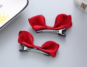 Détail de pinces à cheveux à nœuds en satin rouge avec base métallique argentée