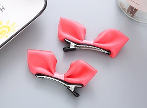Gros plan de pinces à cheveux à nœuds en satin rose avec clips en métal argenté