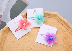 Detailed set of 3 pastel mesh flower hair clips with colorful pom-poms on a display card