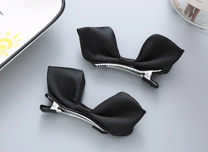 Détail de deux nœuds de cheveux en satin noir avec pinces bec de canard sur fond gris