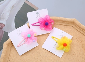 Detailed view of chiffon flower hair clips in pink, rose and yellow on a display card