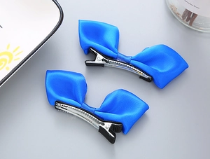 Détail de barrettes à nœuds en satin bleu avec base crocodile et gaine en tissu