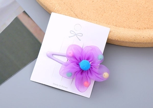 Detailed close-up of a purple mesh flower hair clip with colorful beads and blue center