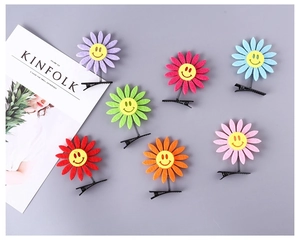 Detail view of colorful felt smiling flower hair clips with dynamic metal spring clips
