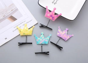 Detail of four crown-shaped spring hair clips in macaron colors for children and girls