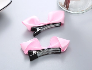 Détail de barrettes à nœuds en soie rose avec base en métal argenté pour filles