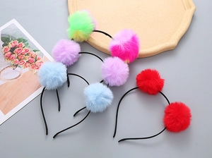 Detailed view of colorful furry pom pom headbands for girls in red blue and purple