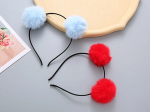 Close-up of cute children's headbands with fluffy red and light blue pom-pom decorations