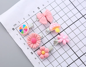 Detailed view of 6 candy-colored resin flower and bow hair clips on a scale grid