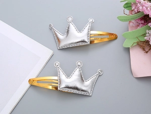 Dettaglio di fermagli per capelli a corona in similpelle argento con cuciture e clip dorate
