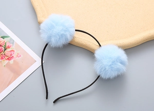 Close-up of cute light blue fluffy pom-pom headbands for girls with soft faux fur texture