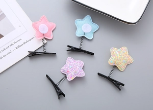 Detailed view of four colorful star spring hair clips with fabric and glitter finishes