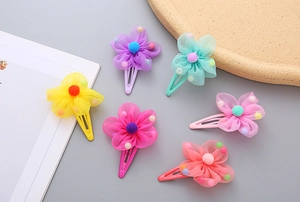 Detailed view of six colorful mesh flower hair clips with soft pom-poms and metal clips