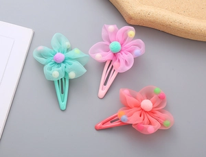 Detail of three mesh flower hair clips in mint green, pink and orange colors for girls