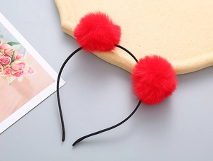 Detail of red fluffy pom-poms on a black headband for girls festive occasions
