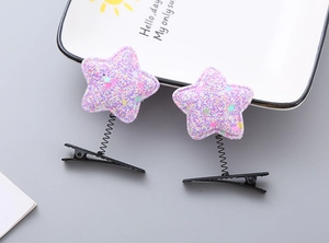 Close-up of purple star-shaped spring hair clips with glitter sequins and metal duckbill clip