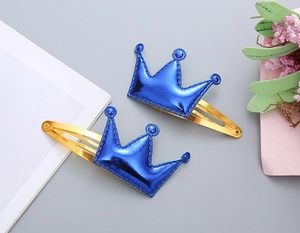 Dettaglio di due fermagli a corona per bambine in pelle PU blu metallizzato e oro