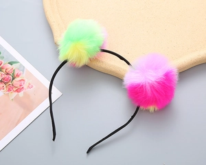 Detail view of girls headband with colorful faux fur pom-poms on a light gray background