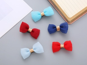 Close-up of five colorful seersucker bow hair clips for girls on a minimalist desk setup