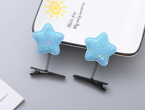 Detail of star-shaped spring hair clips in light blue glitter with colorful star accents