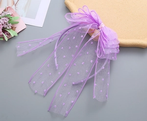 Detailed view of purple mesh headband with large bow and white polka dot ribbon streamers
