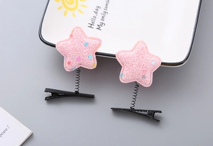 Close-up of pink glitter star hair clips with soft plush texture on a white plate