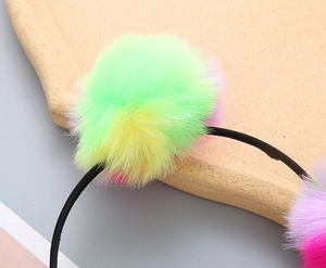 Close-up of colorful plush pom-poms on a children headband showing soft fuzzy textures
