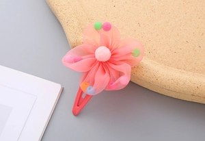 Close-up of pink flower hair clip with colorful pom-poms and metal BB hair pin