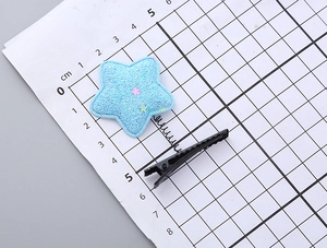 Detail view of a 5.5cm blue sequin star hair clip on a metric scale measurement board