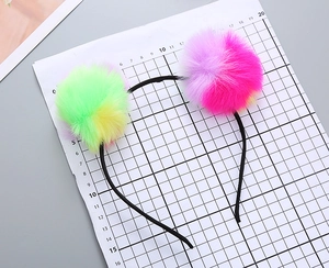 Detail showing colorful plush pom-poms on kids headband with rainbow faux fur design