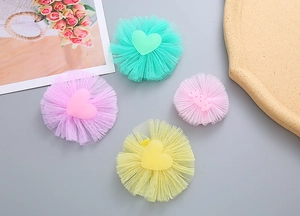 Close-up of four colorful tulle hair clips with heart and candy shapes for girls