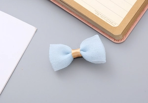 Detail of light blue seersucker bow hair clip with golden silk center on desk