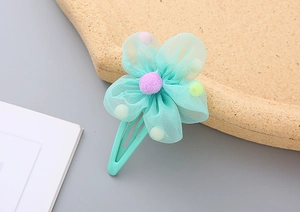 Detail of mint green organza flower hair clip with purple pom-pom and tiny beads