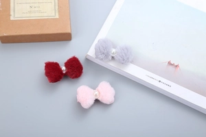 Dettaglio di fermagli per capelli in peluche a fiocco rosso, grigio e rosa con perla