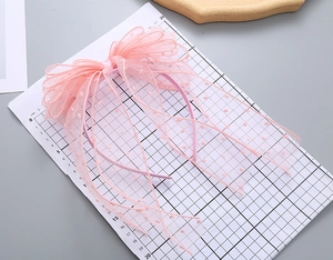 Close-up of pink polka dot mesh bow headband for girls with measuring ruler detail