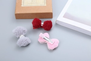 Dettaglio di fermagli per capelli in peluche con fiocchi, perle e clip in rosso, grigio e rosa