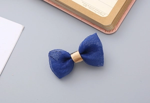 Detailed view of a handmade navy seersucker bow clip with gold satin ribbon accent