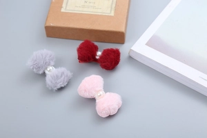 Dettaglio di fermagli per capelli in peluche con fiocchi rossi, grigi e rosa e perle