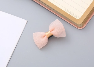 Detail of pink mesh bow hair clip with gold satin center on a desk setting