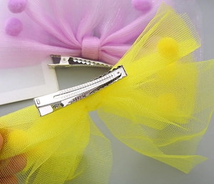Détails des barrettes nœuds en maille colorée avec pompons et pinces crocodiles en métal