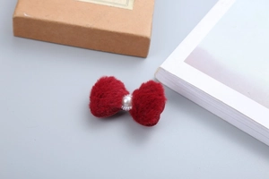 Dettaglio del fermaglio per capelli a fiocco in peluche rosso con perla per l'inverno