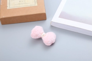 Dettaglio di un fermaglio per capelli a fiocco rosa con pelliccia sintetica e perla