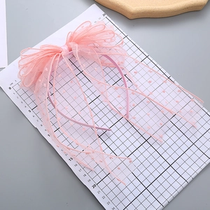 Pink polka dot mesh bow headband for girls with long ribbons on a white display board