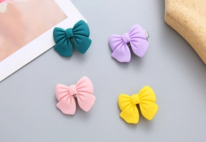 Close-up of four matte candy-colored bow hair clips in green, purple, pink and yellow