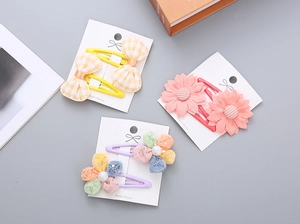 Close-up of children's floral bow hair clips with pearls and lace on a display card