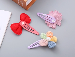 Detail of floral and bow hair clips with mesh petals and imitation pearls for girls