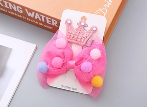 Detail von rosa Netzschleifen-Haarspange mit bunten Pompons und gestrickter Krone