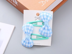 Close-up of blue gingham bow hair clips on a white display card for girls